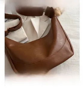 Close-up of brown synthetic leather texture and adjustable strap on a dumpling bag