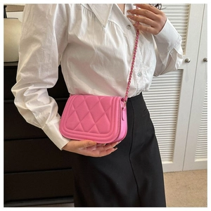 On-body shot of a pink quilted crossbody bag featuring a golden metal chain strap