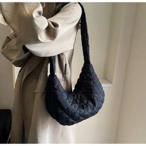 Detail of black quilted nylon dumpling bag showing high-quality texture and wide shoulder strap