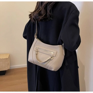 Nahaufnahme der beigen Lederhandtasche mit Goldkette und verstellbarem Gurt am Model