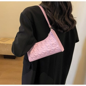 Detail of pink underarm bag with Y-shaped embossed pattern on model in black blazer