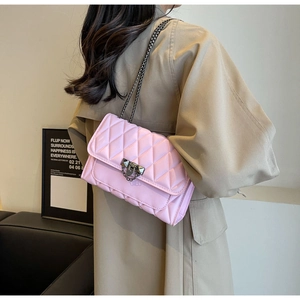 Rear side view of a pink quilted chain bag with dark metal clasp worn by a model