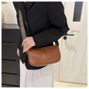 Detail der braunen Vintage-Lederhandtasche mit buntem, breitem Schultergurt im Ethno-Stil