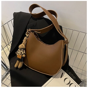 Close-up of brown leather saddle bag with a cute rabbit charm and wide strap