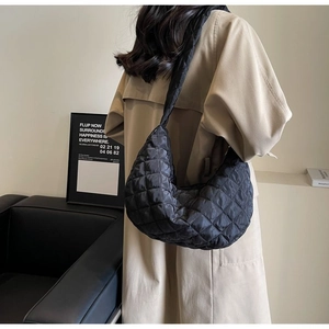 Detail of black quilted nylon crescent bag showing soft diamond texture and wide strap