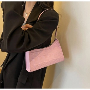Close-up of pink underarm bag with geometric star embossing worn on model's shoulder