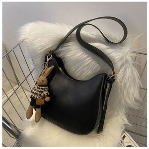 Detail of black leather hobo bag with a cute brown rabbit charm in a wire basket