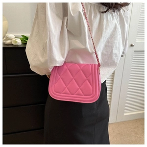 Detailed view of pink quilted crossbody bag with woven chain strap worn by a model
