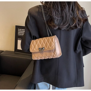 Close-up of beige quilted crossbody bag with diamond pattern and metal chain strap