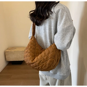 Brown quilted nylon hobo bag with diamond pattern shown on a shoulder