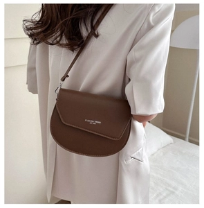 Detail of a dark brown matte leather saddle bag with white Fashion Trend lettering