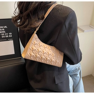 Close-up of beige underarm bag featuring unique 3D star texture and adjustable strap