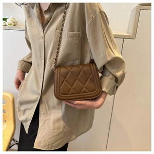Detailed view of brown quilted leather crossbody bag with elegant gold chain strap