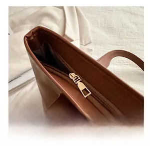 Close-up of smooth gold metal zipper closure on premium brown leather tote bag
