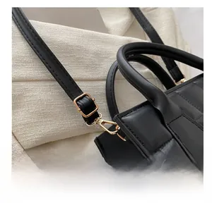 Macro detail of the golden adjustable buckle and black quilted leather strap on handbag