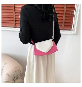 Detailed back view of a rose pink heart-shaped crossbody bag on a model in a home setting