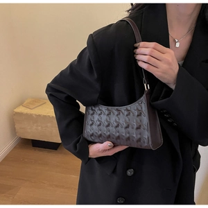 Detail of dark brown underarm bag with geometric embossing and sleek gold hardware