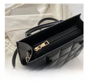 Macro view showing the smooth gold metal zipper on a black quilted leather handbag