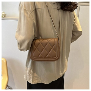 Close-up of brown quilted crossbody bag with gold-tone interwoven chain strap detail