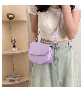 Crossbody view of light purple leather saddle bag with Chic Moment logo detail