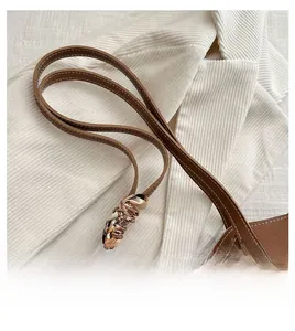 Detail of brown leather tote bag handle featuring a stylish printed silk scarf decoration