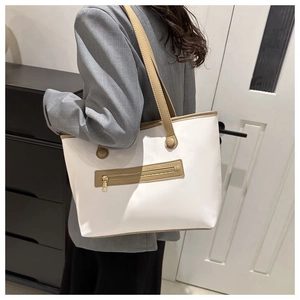 Close-up of a white tote bag with brown straps and a front zipper pocket on a model