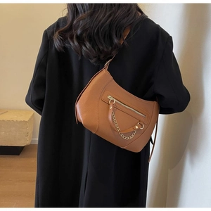 Detail der braunen Schultertasche aus genarbtem Leder mit eleganter goldener Reißverschlusskette