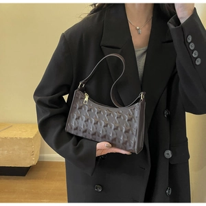 Detail of star-embossed texture on dark brown baguette bag with golden zipper hardware