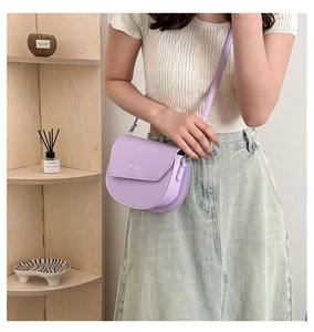 Detail of lavender saddle bag worn crossbody with minimalist logo and leather strap