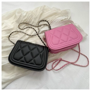 Close-up of black and pink quilted leather bags with gold chain straps on white fabric