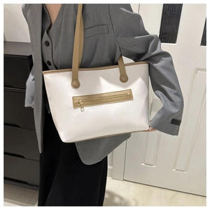 Close-up of a large tote bag showing white leather texture and khaki strap details