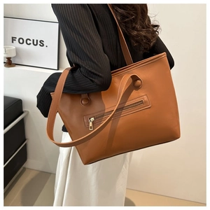 Detail view of large caramel brown tote bag with zipper pocket and long shoulder strap