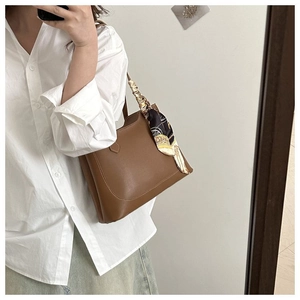 Brown leather tote bag with decorative floral scarf and minimalist curved top opening detail