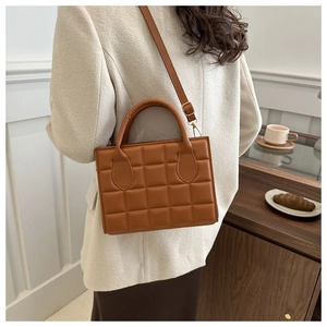 Detail showing brown quilted square handbag with adjustable strap on a female model