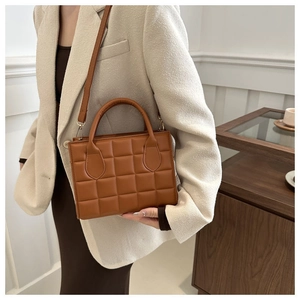 Close-up of brown quilted faux leather handbag with golden hardware and slender strap