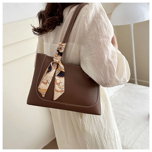 Detail of dark brown leather tote bag with contrast stitching and floral silk scarf