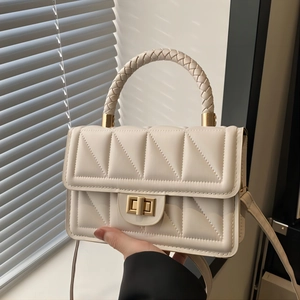 Chic cream quilted flap bag with woven handle and gold twist lock in soft natural light