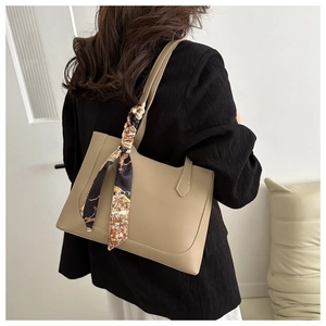 Detail of khaki faux leather tote bag with floral scarf handle on model shoulder