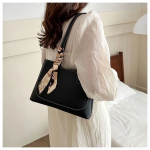Detail of black tote bag with white contrast stitching and printed silk scarf on handle