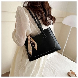 Detail of black PU leather tote bag with white stitching and floral scarf handle