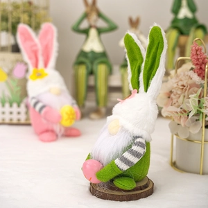 Detail of Easter gnome plush with pink ears and striped hat holding a colorful egg