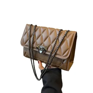 Caramel quilted crossbody bag with chain strap and metallic lock detail on white background