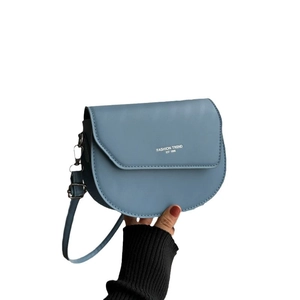 Handheld light blue saddle crossbody bag with fashion trend lettering on clean background
