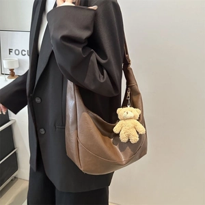 Retro dark brown crescent shoulder bag with plush bear pendant shown on model