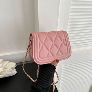 Pink quilted crossbody bag with gold chain strap shown being held in hand