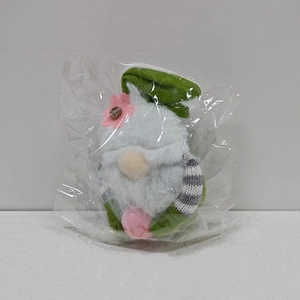 Detail of Easter gnome featuring pink flower on green hat and striped knit sleeves