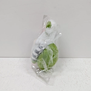 Close-up of Easter plush gnome with pink ears and green fabric in transparent packaging