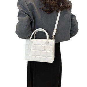 Minimalist white quilted handbag with gold hardware shown on model for size perspective