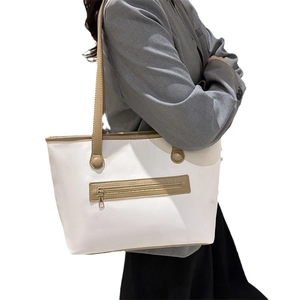 Large white and khaki contrast tote bag in textured leather shown on model's shoulder