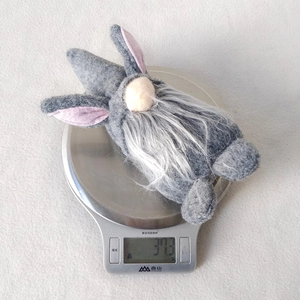 Detail shot of a grey Easter gnome plush on a kitchen scale showing 37.3g weight